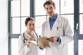 Two dedicated doctors smiling while holding a folder with medical records