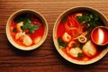 Two deep bowls with Thai tom yam soup with bright tomato sauce and coconut