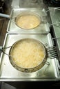 Two deep-fryers frying potatoes in a restaurant kitchen, vertical photo