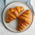 Two delicious croissants on plate and hot drink in mug. Morning French breakfast with fresh pastries. Light gray background, top Royalty Free Stock Photo