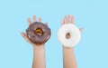 Two delicious donuts with black and white chocolate icing in children`s hands isolated on a blue background. Donuts in children`s Royalty Free Stock Photo