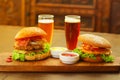 Two delicious hamburgers with beef, onion, tomato, lettuce and cheese with ketchup, mustard and two glasses of beer on Royalty Free Stock Photo