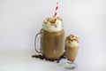 Two Delicious iced coffee or Frappuccino with whipped cream , syrup and a red straw . With Coffee beans isolated on white