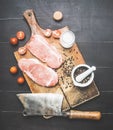 two delicious raw pork steaks on vintage cutting board with meat cleaver, spices and tomatoes, top view Royalty Free Stock Photo