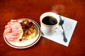 Two delicious sugared ring donuts served on white plate with a cup of hot drink