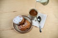 Two delicious sugared ring donuts served on white plate with a cup of hot drink