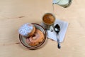 Two delicious sugared ring donuts served on white plate with a cup of hot drink