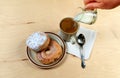 Two delicious sugared ring donuts served on white plate with a cup of hot drink Royalty Free Stock Photo