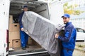 Two Delivery Men Unloading Furniture From Vehicle Royalty Free Stock Photo