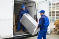 Two Delivery Men Unloading Furniture From Vehicle Royalty Free Stock Photo