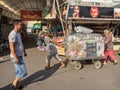 Two delivery persons, a man and a woman, showing efforts pulling a cart in the central market of the capital city of Moldova