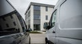 Two delivery vans parked outside a modern office building on a cloudy day ready for work Royalty Free Stock Photo