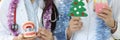 Two dentist doctors are holding a dental instrument on background of Christmas tree