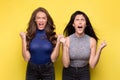 Two women screaming hysterically on yellow background