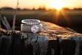 two diamond wedding rings on a weathered stump, backlit by the setting sun