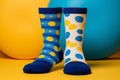 Two different mismatched socks on colorful yellow and light blue geometric shape background. Odd Socks Day, Lonely Sock