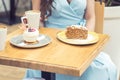 Two different pieces of cakes on the table at cafe on the background of girl with cup of coffee Royalty Free Stock Photo
