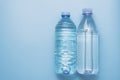 Two different plastic bottles with a sparkle of water on a blue background. Copyspace, place for text, flat lay Royalty Free Stock Photo