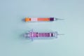 Two different vaccination syringes with the needle uncapped on a textured blue paper background. Royalty Free Stock Photo