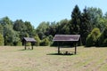 Two dilapidated wooden public benches with makeshift roofs covered with broken roof tiles at local public park