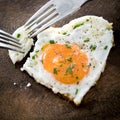 Two dinner forks pricking in a fried egg with heart shape Royalty Free Stock Photo