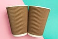 Two disposable cups for hot drinks on a geometric pink and turquoise backgrounds. Paper cups Royalty Free Stock Photo