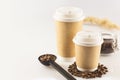 Two disposable eco-friendly cups and ground coffee in a glass jar