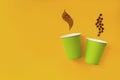 Two disposable paper green cups mock up for coffee to go, which is then recyclable, decorated with coffee beans flat lay on yellow