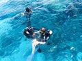 Two divers in black scuba diving suits, a man and a woman with oxygen bottles sink under the transparent blue water in the sea, th Royalty Free Stock Photo