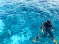 Two divers in black scuba diving suits, a man and a woman with oxygen bottles sink under the transparent blue water in the sea, th Royalty Free Stock Photo