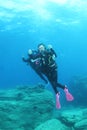 Two divers swimming above rocky bottom