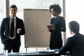 Two diverse business coaches making flip chart presentation at meeting