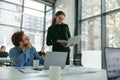 Two diverse business colleagues disscuss biz issue while use laptop in office background Royalty Free Stock Photo