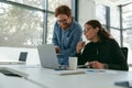 Two diverse business colleagues disscuss biz issue while use laptop in office background Royalty Free Stock Photo