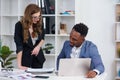 Two diverse businesspeople chatting sitting behind laptop in office. Excited caucasian female sharing ideas or startup Royalty Free Stock Photo