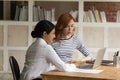 Two diverse businesswomen working on project together, using laptop Royalty Free Stock Photo