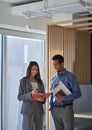 Two diverse coworkers discussing teamwork plan standing in office. Vertical Royalty Free Stock Photo