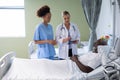 Two diverse female doctors and african american male patient in hospital room talking Royalty Free Stock Photo