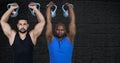 Two diverse fit men working out with dumbbells against copy space on grey brick wall background Royalty Free Stock Photo