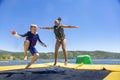 Two diverse kids jumping and playing on a water bounce house on a lake