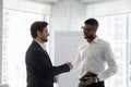 Two diverse smiling business men shaking hands in office boardroom Royalty Free Stock Photo
