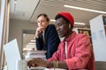 Two diverse students study partners learning together in library, using online database Royalty Free Stock Photo