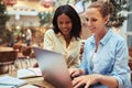 Two diverse young businesswomen smiling while working on a lapto Royalty Free Stock Photo