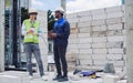 Two diversity male engineers team working, inspecting outdoor at construction site, wearing hard hats for safety, talking, Royalty Free Stock Photo