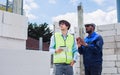 Two diversity male engineers team working, inspecting outdoor at construction site, wearing hard hats for safety, talking, Royalty Free Stock Photo