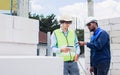 Two diversity male engineers team working, inspecting outdoor at construction site, wearing hard hats for safety, talking, Royalty Free Stock Photo