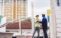 Two diversity male engineers team working, inspecting outdoor at construction site, wearing hard hats for safety, talking, Royalty Free Stock Photo