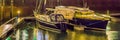 Two docked boats in the harbor decorated with lights