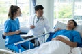 Two doctors caring for a patient lying in a bed in a hospital room with two nurses, a healthcare worker Royalty Free Stock Photo