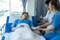 Two doctors caring for a patient lying in a bed in a hospital room with two nurses, a healthcare worker Royalty Free Stock Photo